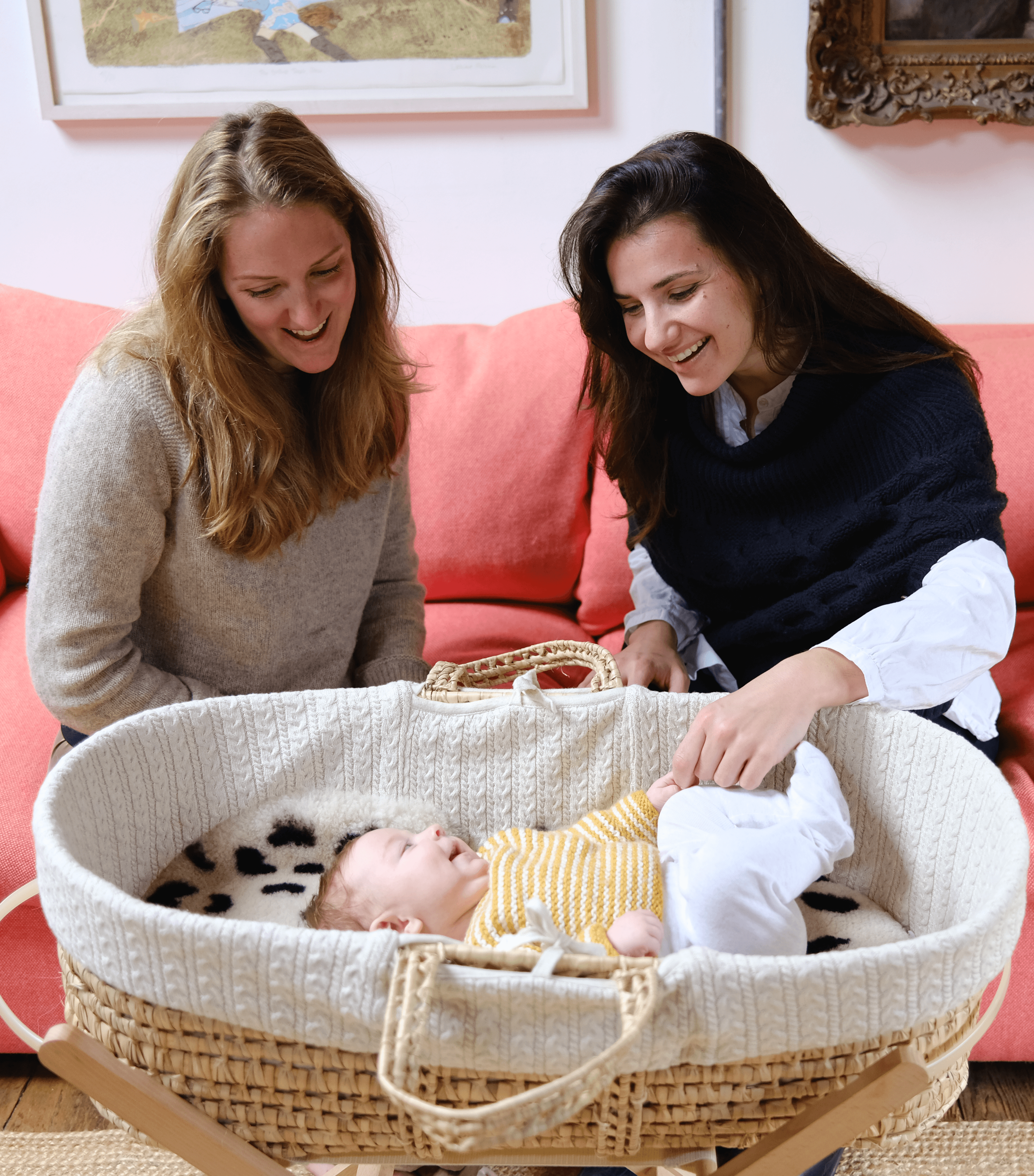 Mother and midwife smiling at a newborn baby in a Moses basket