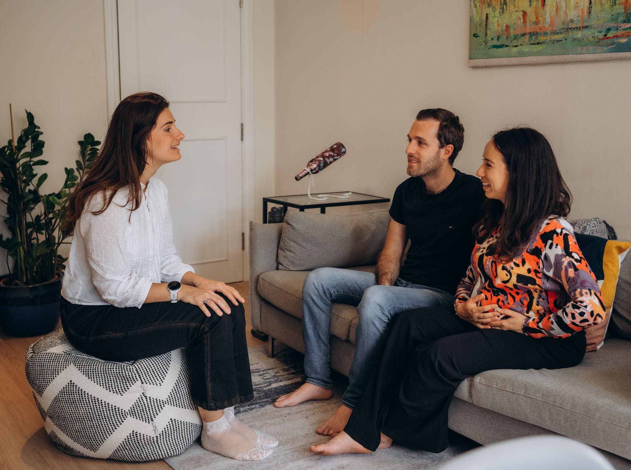 Clarissa, a midwife, talking with a pregnant woman and her partner on their sofa